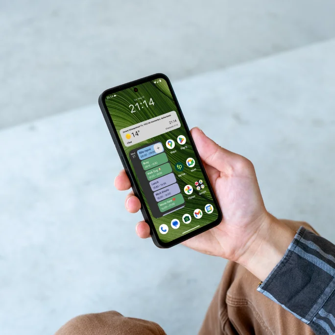 Photography of a hand holding a Fairphone Gen. 6 and various productivity widgets on screen